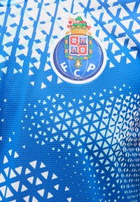 Μπλε και λευκή αθλητική φανέλα με τριγωνικό σχέδιο και το έμβλημα της ποδοσφαιρικής ομάδας FC Porto στο κέντρο.