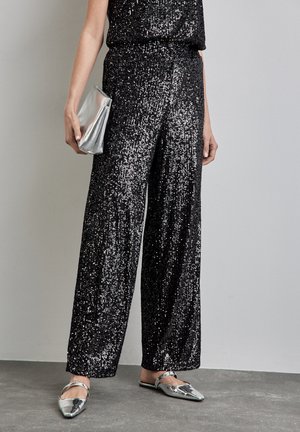 Schwarze Pailletten-Hosen mit weitem Bein und glänzender Oberfläche, kombiniert mit metallic-silbernen Ballerinas und einer passenden silbernen Clutch. Weiche Textur und ansprechendes Design.