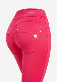 Pantaloni in tessuto elastico fucsia brillante con vita alta, caratterizzati da un logo dorato, due tasche posteriori e dettagli di cucitura decorativa.