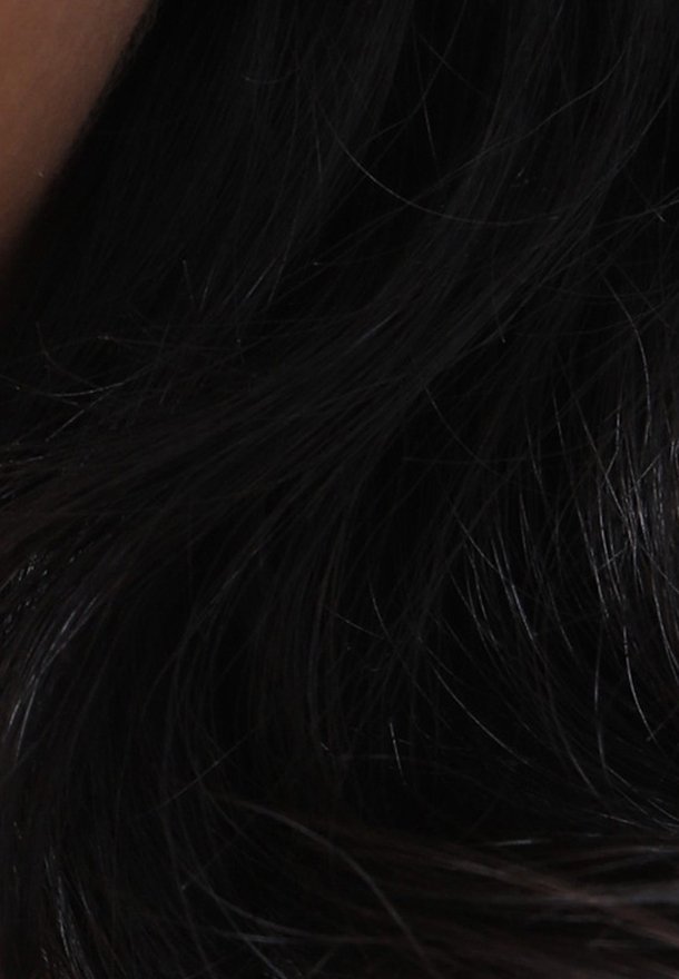 Longs cheveux noirs avec quelques mèches visibles et une petite zone de peau sur le côté gauche.