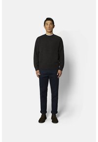 Pull en tricot gris foncé avec col rond, associé à un pantalon bleu marine et des bottes marron à lacets, présenté sur un fond uni.