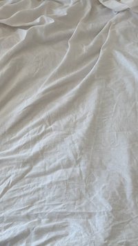 Tela de lino blanca con una textura arrugada, drapeada y superpuesta en suaves pliegues, creando una apariencia natural y fluida.