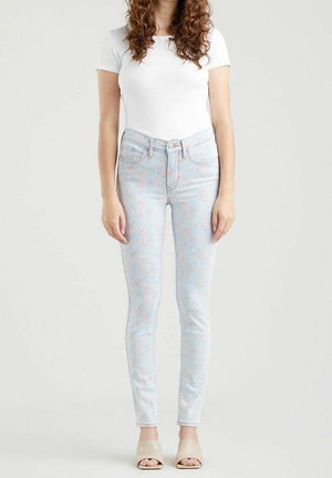 Vaqueros ajustados de color azul claro con un patrón floral en colores pastel. Están hechos de denim, tienen un diseño de cinco bolsillos y cuentan con un cierre de cremallera y botón.