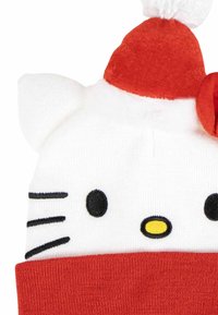 Cappello di maglia bianco con accenti rossi, caratterizzato da un design con faccia di gatto, occhi ricamati neri e un pon-pon in cima. Tessuto morbido con risvolto.