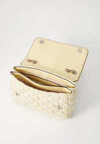 Bolso de mano acolchado en tweed amarillo y blanco con un exterior de tela, cierres de botón dorado y un interior amarillo suave con compartimentos.