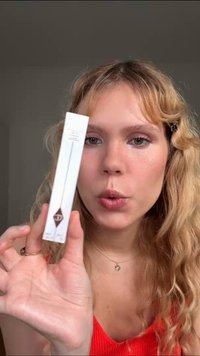 Clear packaging with a white base features a geometric design and branding. Inside, a slender wand with a pointed tip is visible.