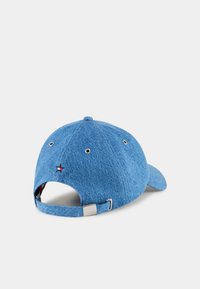 Jeanske baseballkeps i ljusblått med böjd skärm, justerbar rem och liten broderad logotyp i rött och vitt på baksidan.
