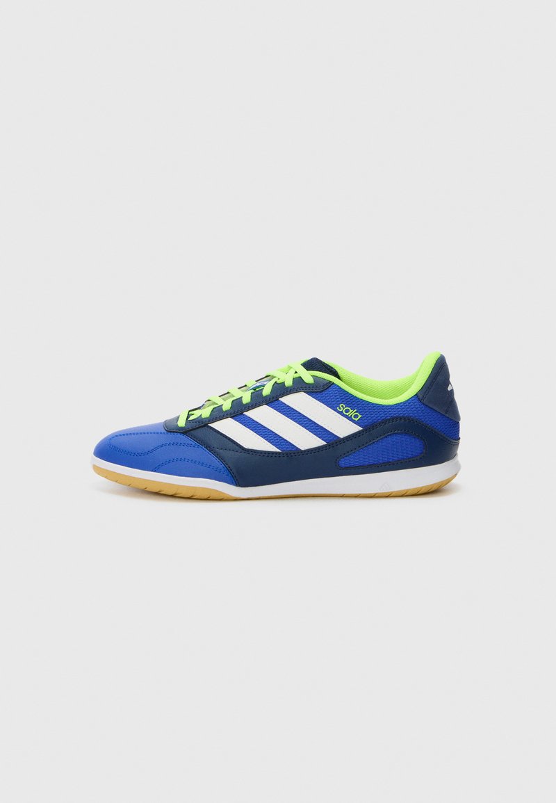 Blauwe en groene sportieve schoen met een gestructureerde bovenkant, witte strepen en contrasterende neon veters. De zool is van lichtbruin rubber.