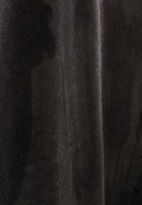 Genomskinligt svart tyg med en slät textur och subtil lyster, som visar fina vertikala ribbade mönster genom hela.