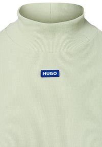 Miętowozielony sweter z golfem w prążki z niebieskim haftowanym logo "HUGO" z przodu. Miękka tekstura, dopasowany krój.