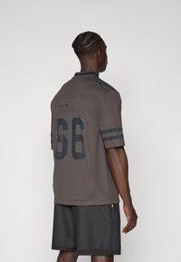 Tamno siva Miami Dolphins dres s kratkim rukavima, s crnim ovratnikom, ikonovanim logotipima i brojem igrača "66" istaknutim na leđima.