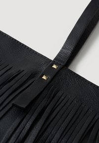 Bolso de piel negra con flecos verticales y dos tachuelas doradas en la correa, con un acabado liso y bordes limpios.