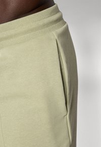 Lichtgroene sweatpants met een gladde textuur, elastische tailleband en zijzakken. Heeft een minimalistisch ontwerp zonder patronen.