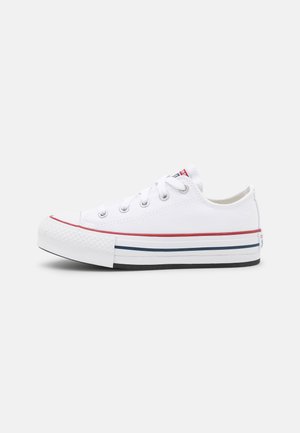 Witte canvas sneakers met een rood en marineblauw gestreept rubberen zool, vetersluiting en teencap. Voorzien van metalen oogjes en een gestructureerde neus.