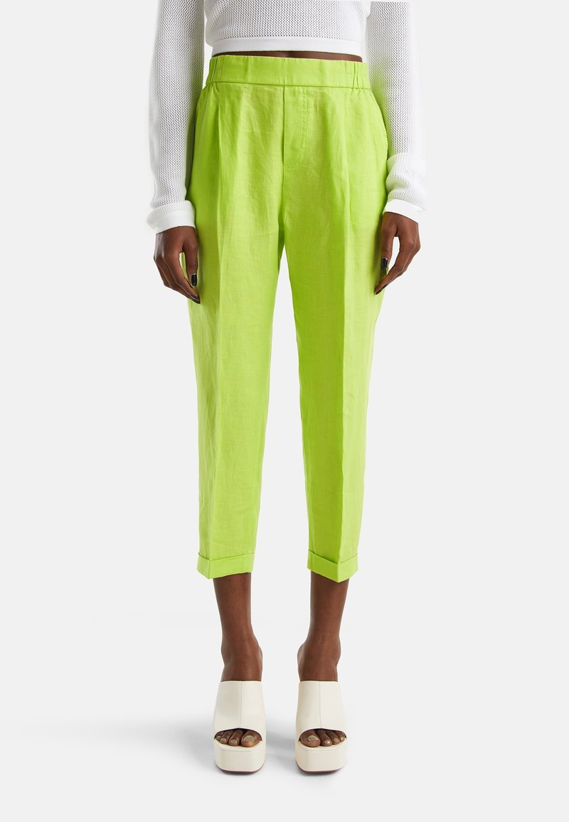 Limegröna linnbyxor med avslappnad passform, kort längd och uppvikta fållar. Bärs med vita platåklackar.