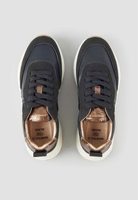 Marineblaue Sneaker mit strukturiertem Obermaterial, Schnürdesign und golden Akzenten. Leichte weiße Sohle für den Kontrast. Das Innere zeigt das Markenlogo.