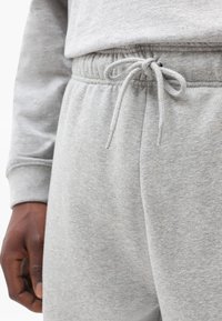 Gray cotton sweatpants with an elastic waistband and drawstring; features a soft texture and a close-up of the waistband detailing.