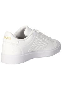 Biele športové tenisky vyrobené z syntetického materiálu, s hladkým povrchom, trojpruhovým dizajnom a zlatým logom na päte.