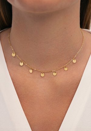 Collar de cadena de oro con pequeños colgantes en forma de disco espaciados uniformemente a lo largo de la cadena, sobre un tono de piel neutro.