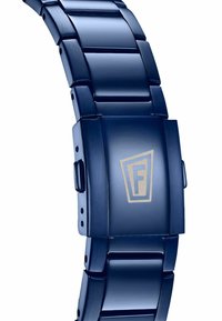 Orologio con cinturino in metallo blu dal finitura lucida, con maglie piatte e una chiusura decorata con un logo geometrico dorato. Texture liscia su tutta la superficie.