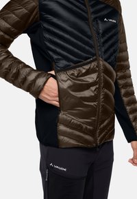 Giacca isolante con pannelli marroni e neri, design trapuntato e tasche con zip. Texture morbida con tessuto resistente per l'uso all'aperto.