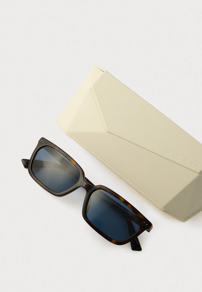 Rectangular tortoiseshell sunglasses with dark blue lenses next to a beige Jimmy Choo branded case on a white background.