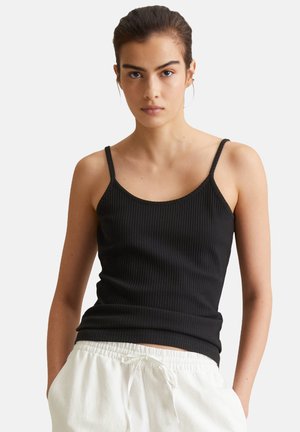 Débardeur noir à côtes avec de fines bretelles, design ajusté et encolure dégagée, associé à un pantalon léger avec cordon de serrage.