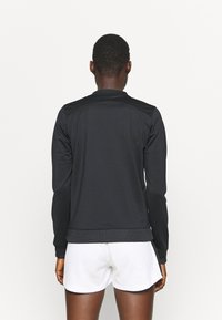 Black athletic jacket made of smooth fabric, featuring a ribbed hem and cuffs, with a simple, minimalistic design.
