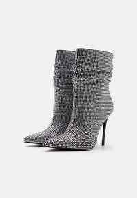 Bottines à talons hauts recouvertes de strass argentés, avec un bout pointu et une texture froncée en haut.