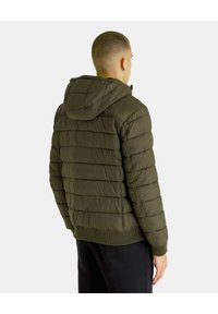 Olivza zaļa puffer jaka ar kapuci, ar quilting sadaļām, ribotiem piedurkņu galiem un aizdari. Mīksta, strukturēta apdare.