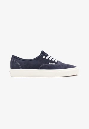 Baskets basses Vans en daim bleu marine avec lacets blancs, coutures blanches et semelle épaisse en caoutchouc blanc.