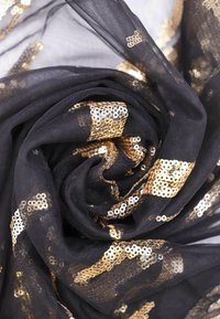 Scialle nero trasparente con paillettes dorate, caratterizzato da un design testurizzato a motivo vorticoso. Materiale leggero e flessibile.