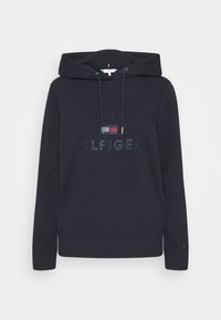 Granatowa bluza z kapturem wykonana z miękkiej bawełny, z regulowanym sznurkiem przy kapturze, z logo "TOMMY HILFIGER" z kamieniami ozdobnymi na przodzie.