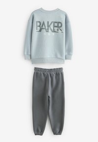 Lys blå sweatshirt med "BAKER" grafik på forsiden, parret med grå sweatpants med elastisk talje og tapered ben.