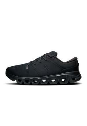 Baskets de sport noires avec semelle texturée, tige en mesh et design à lacets, montrées de profil sur fond blanc.