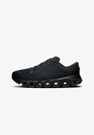 Baskets de sport noires avec semelle texturée, tige en mesh et design à lacets, montrées de profil sur fond blanc.
