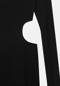 Haut noir à manches longues côtelé avec une découpe distinctive sur le côté. Le tissu présente une finition texturée, mettant en valeur le design unique.