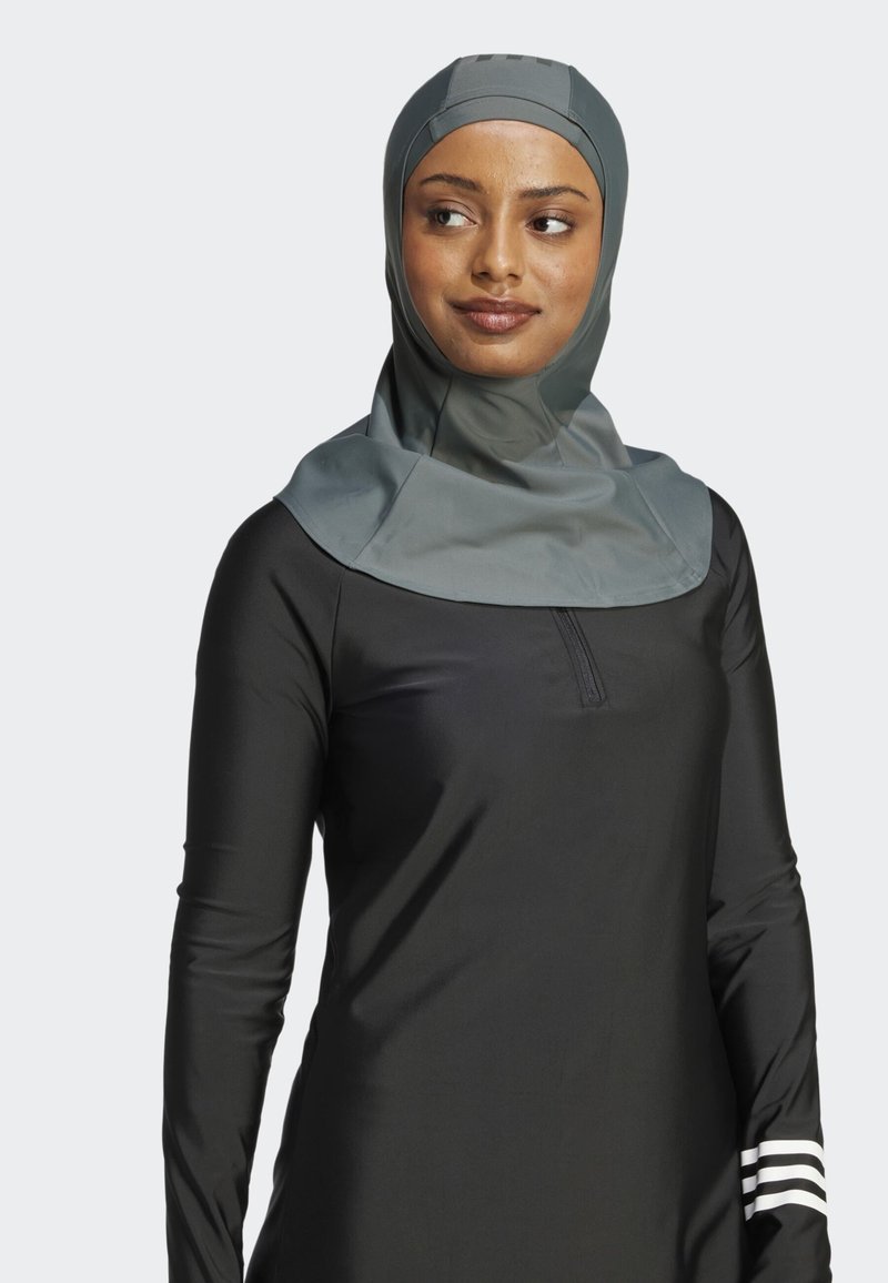 Abbigliamento sportivo con un design nero elegante. Presenta un hijab grigio chiaro con una texture liscia e un collo con zip a un quarto. Strisce bianche sulle maniche.