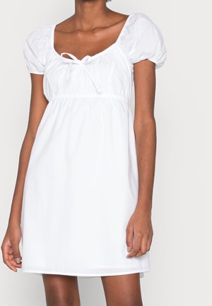 Robe blanche avec des manches bouffantes et un décolleté carré. Dotée d'un cordon de serrage à l'avant, en tissu lisse, et d'une coupe décontractée.