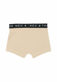Beige pamut boxer nadrág fekete derékkal, amelyen fehér szöveg olvasható: "AZ ÚJ." Simaság jellemzi, rövid lábakkal és kerek nyílásokkal.