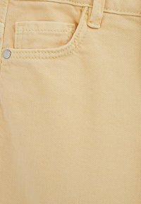 Světlá žlutá denimová látka s malou přední kapsou, diagonální texturou tkaní a jemnými šicími detaily.