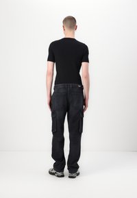 Svart kortermet t-skjorte kombinert med mørke denim cargobukser med sidelommer og et logodetalj på baksiden.