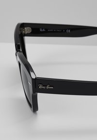 Ochelari de soare Ray-Ban negri au un cadru dreptunghiular, o finitionare netedă și detalii cu logo argintiu pe brațul exterior. Fabricat în Italia.