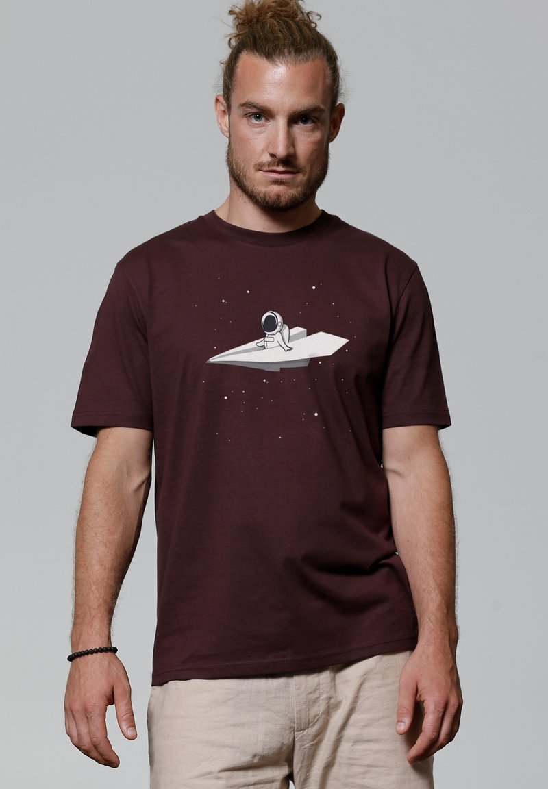 Bordeaux katoenen t-shirt met een afbeelding van een astronaut op een papieren raket tegen een sterry achtergrond. Korte mouwen en een losse pasvorm.