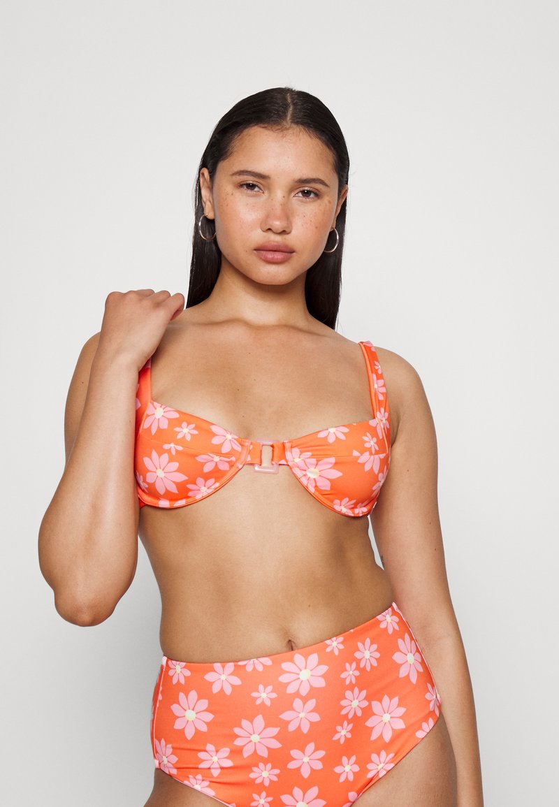 Conjunto de biquíni em duas peças com padrão de flores laranja e margaridas cor-de-rosa. O sutiã tem um design estruturado com alças ajustáveis e um fecho central.