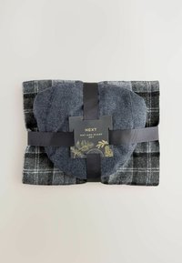 Folded dark gray plaid scarf with a textured dark blue hat secured by a black ribbon and a label reading "NEXT Hat and Scarf Set."