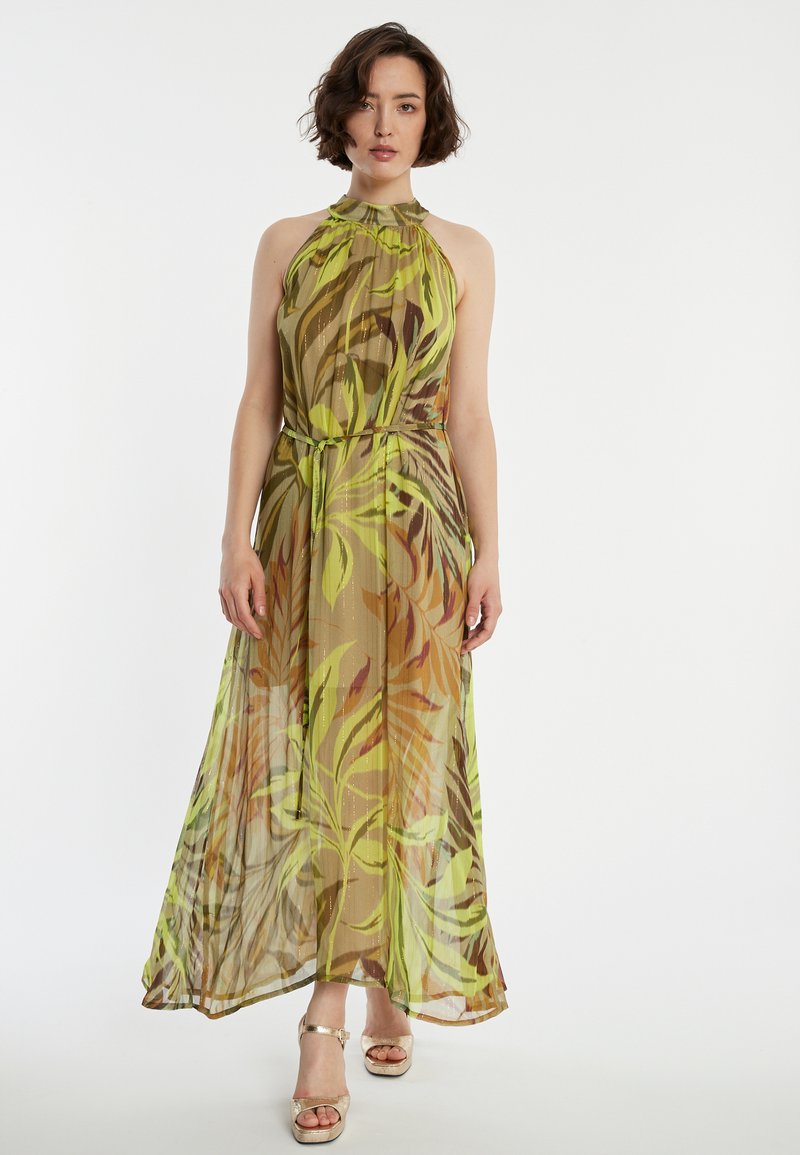 Robe maxi en tissu léger et translucide avec des motifs de feuilles vertes et brunes. Présente un col montant et une ceinture à la taille pour un ajustement réglable.