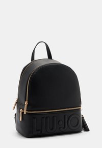 Schwarzer strukturierten Leder-Rucksack mit runder Form, goldenen Hardware-Reißverschlüssen und geprägtem Logo-Detail auf der Vorderseite; verfügt über einen oberen Griff.
