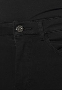 Černé džíny s klasickým designem, se zapínáním na kovový knoflík, předními kapsami a kontrastním prošíváním. Měkký denimový materiál.