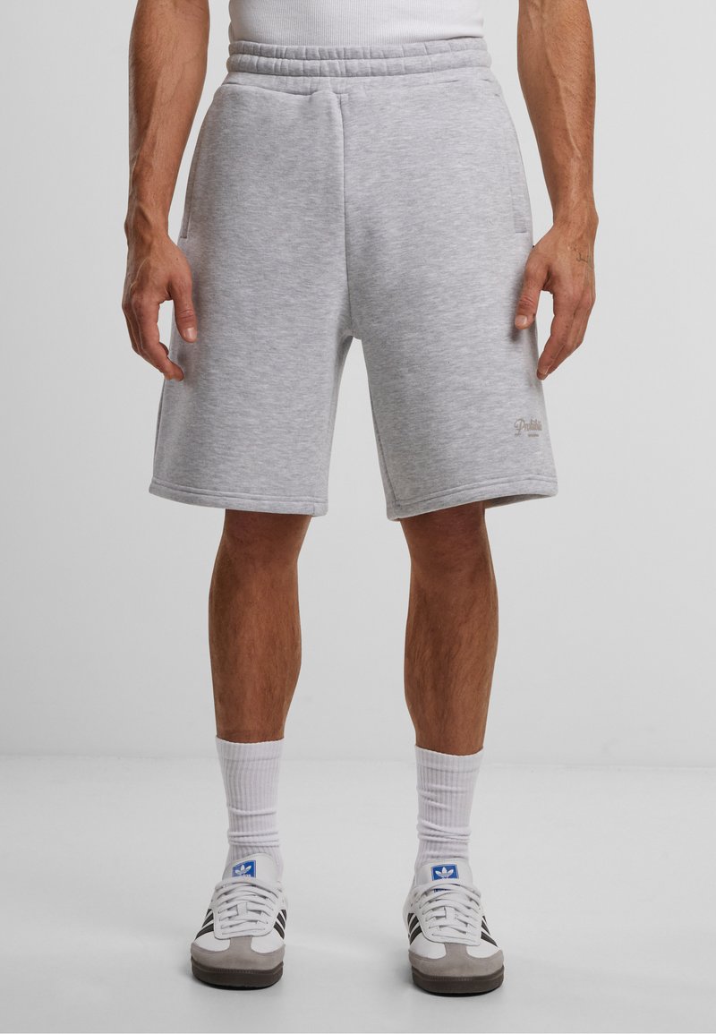 Grå bomullsmix shorts med elastisk midje, side lommer og en liten logo aksent. Brukt med hvite sportssokker og joggesko.